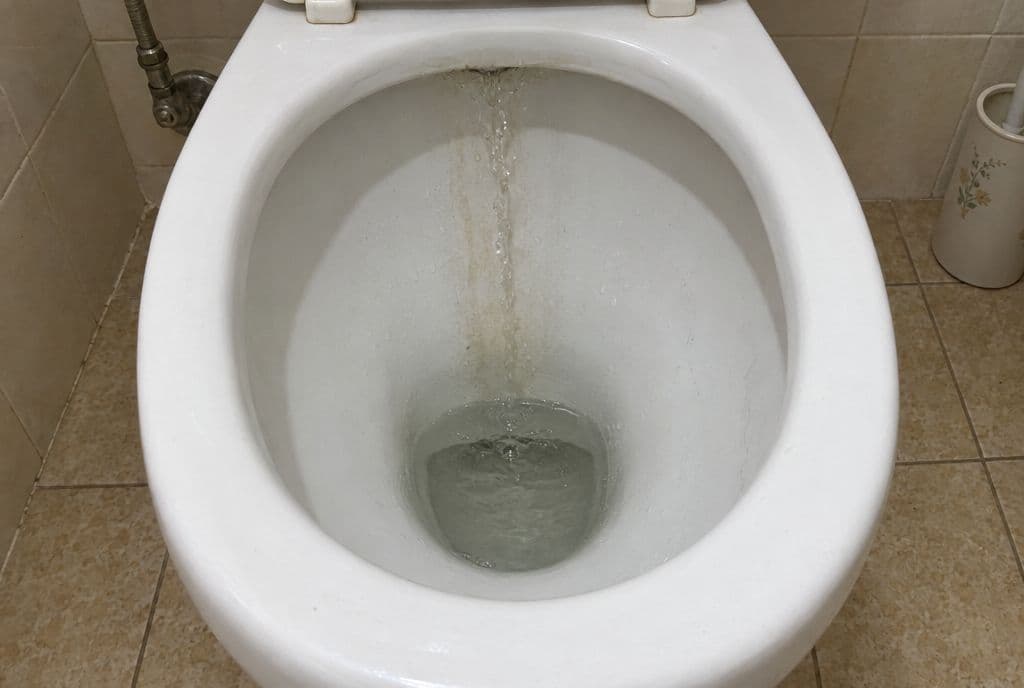 Hilo de agua cayendo sin parar por la taza del inodoro desde la cisterna