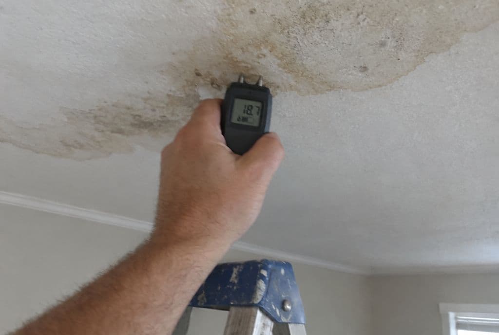 Técnico midiendo la humedad de una mancha del techo con un humidímetro de puntas