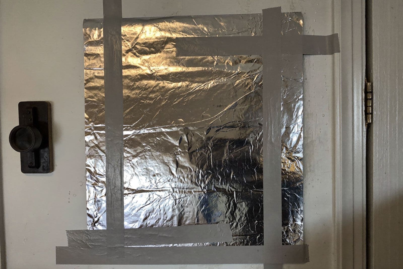 Cuadrado de papel de aluminio sellado con cinta sobre una mancha de humedad en la pared